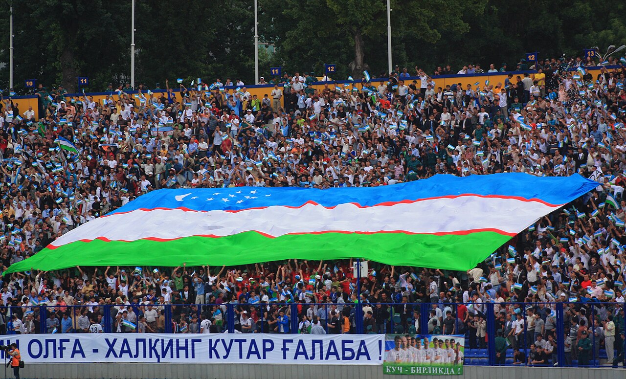 Uzbekistan supporters holding a large national flag before a football match