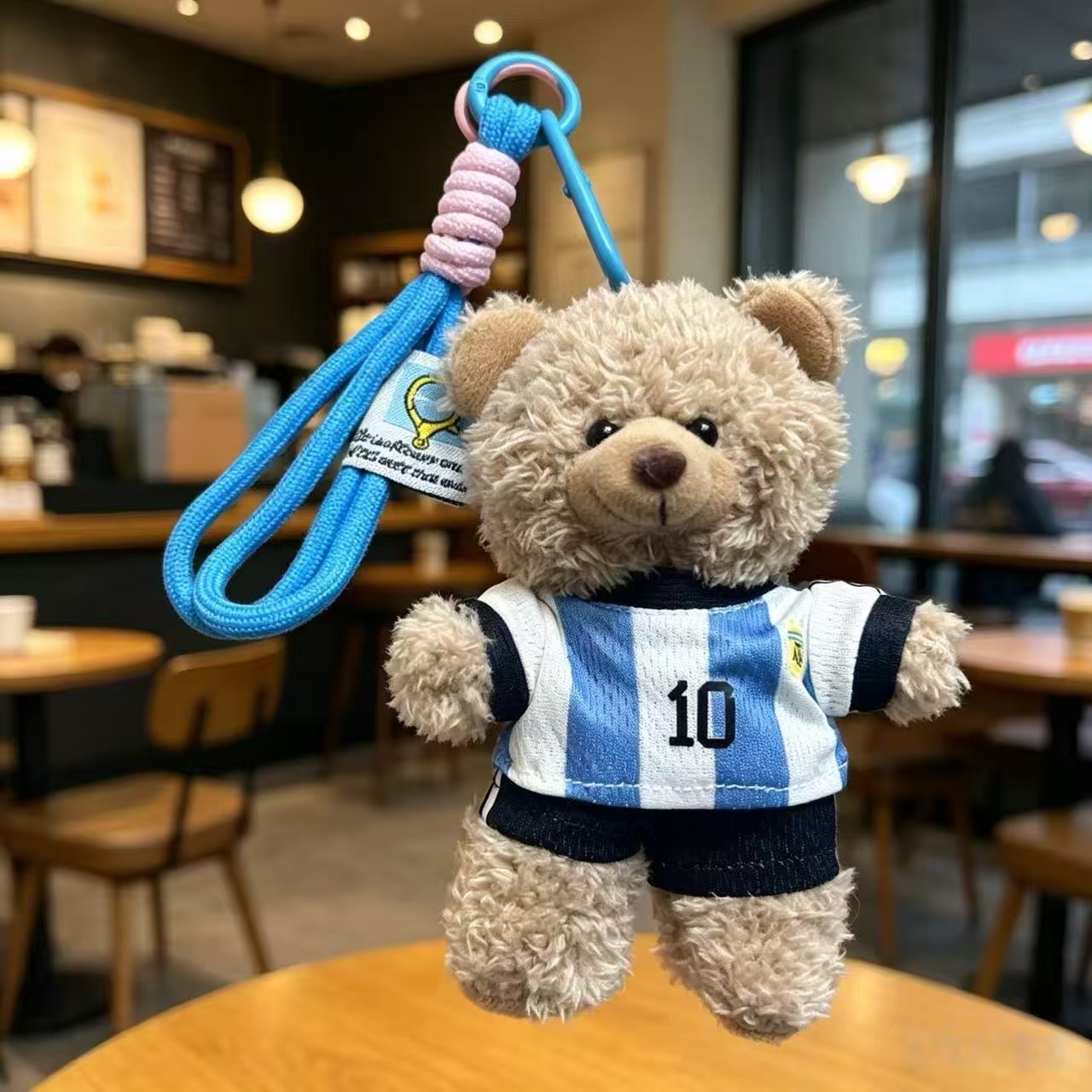 Brown plush bear keychain in a striped football shirt