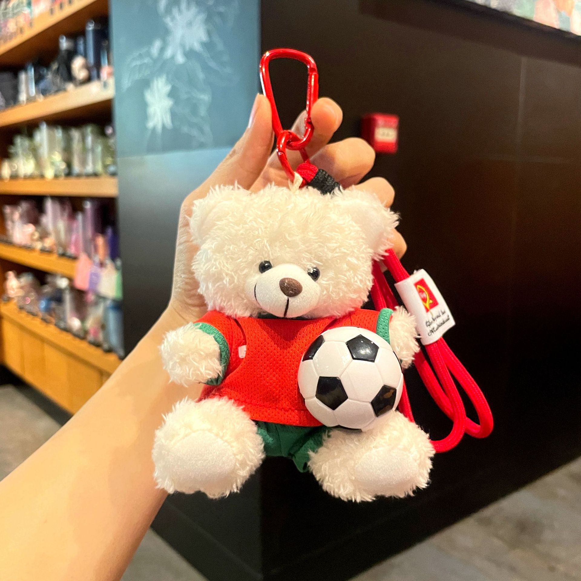 Plush bear keychain in red kit holding a classic football